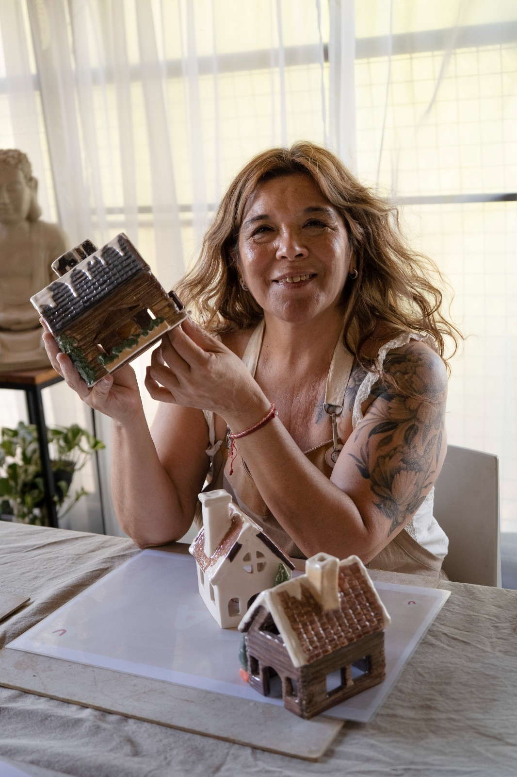 Ceci sosteniendo una de sus casitas de cerámica en el taller